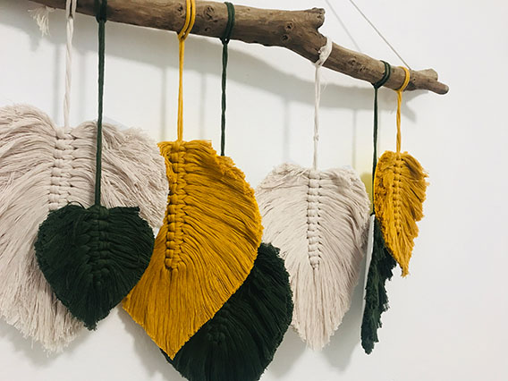 Wall decoration of leaves made out of wool hanging from a branch