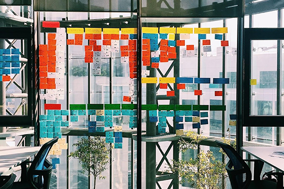 Mejorar productividad. Una imagen de una oficina con un pared cubierto en papeles de notas en colores distinctas.