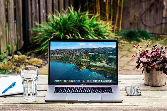 What is a freelancer? An image of a laptop on a wooden table situated outside in a beautiful garden.